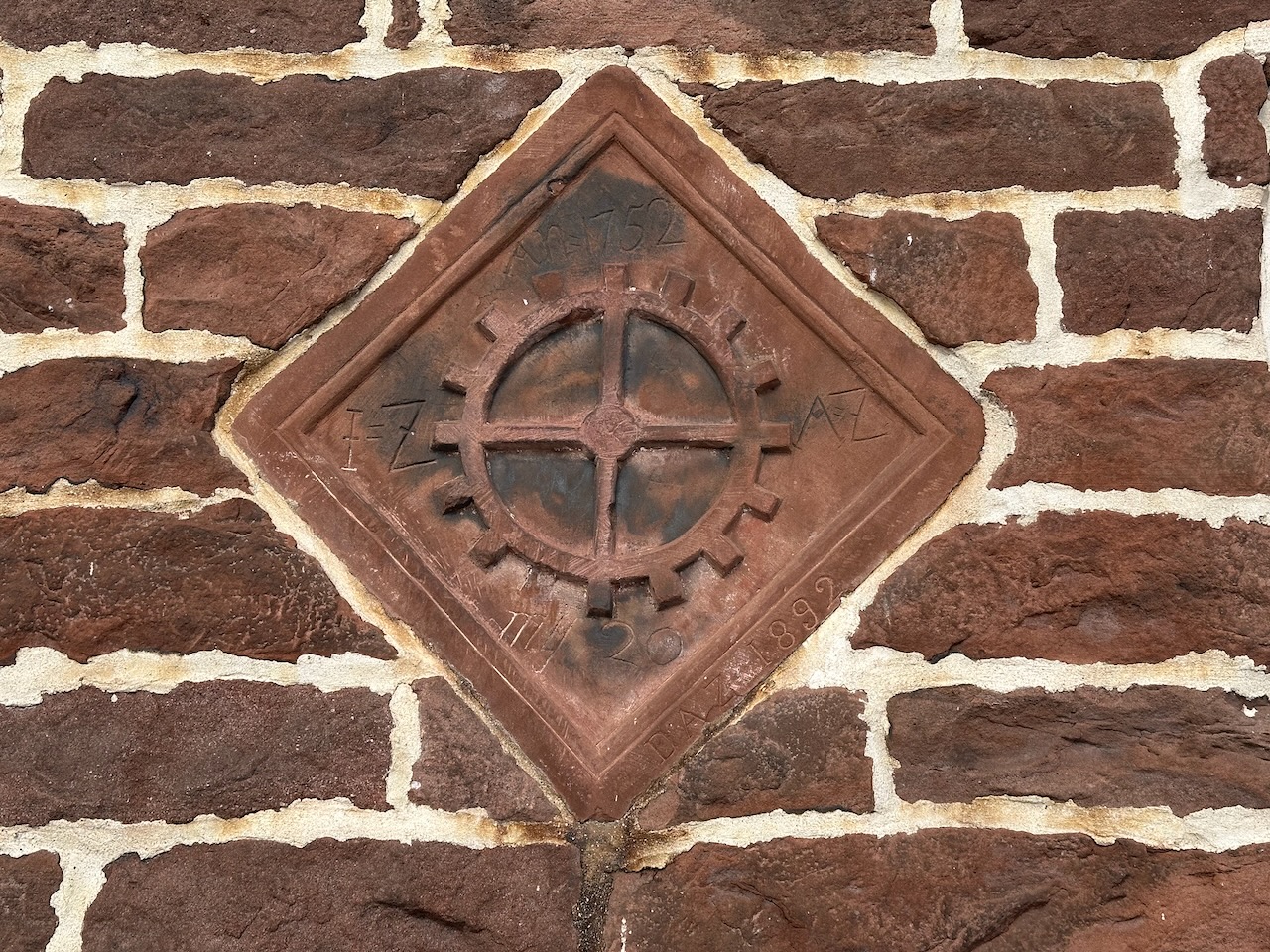 Diamond-shaped date stone with paddle wheel and names of builders and year of construction.