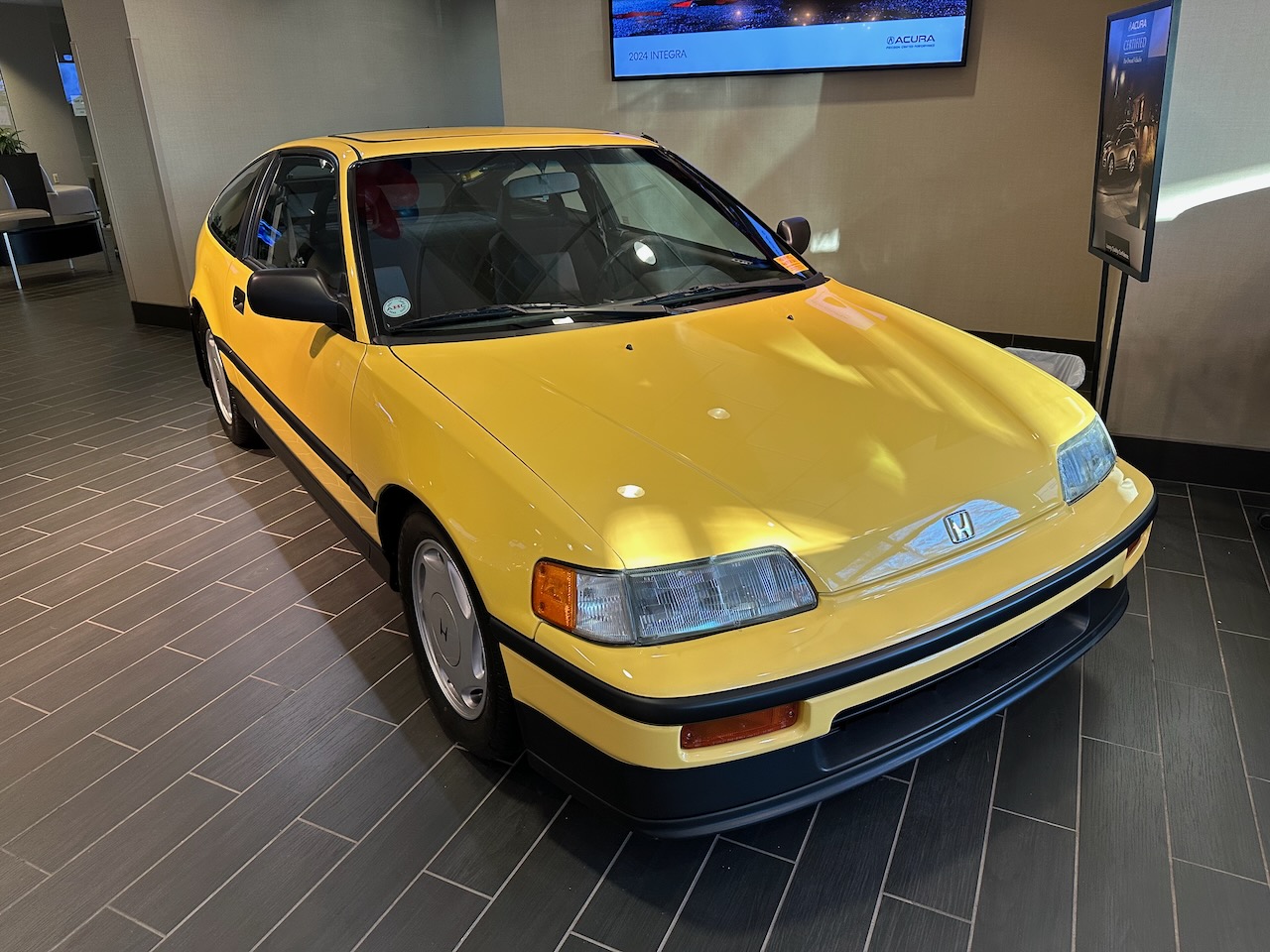 Honda CR-X in yellow on showroom floor. 