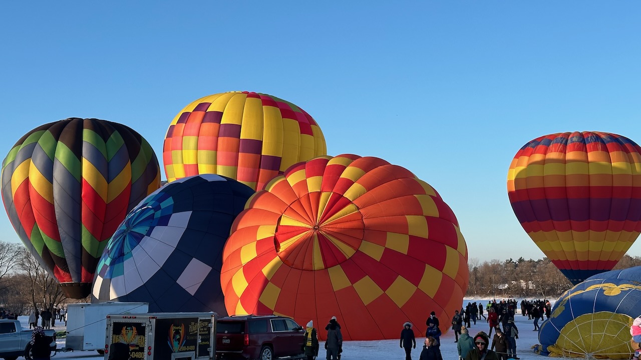 Five hot air balloons starting to inflate and rise from ground. 