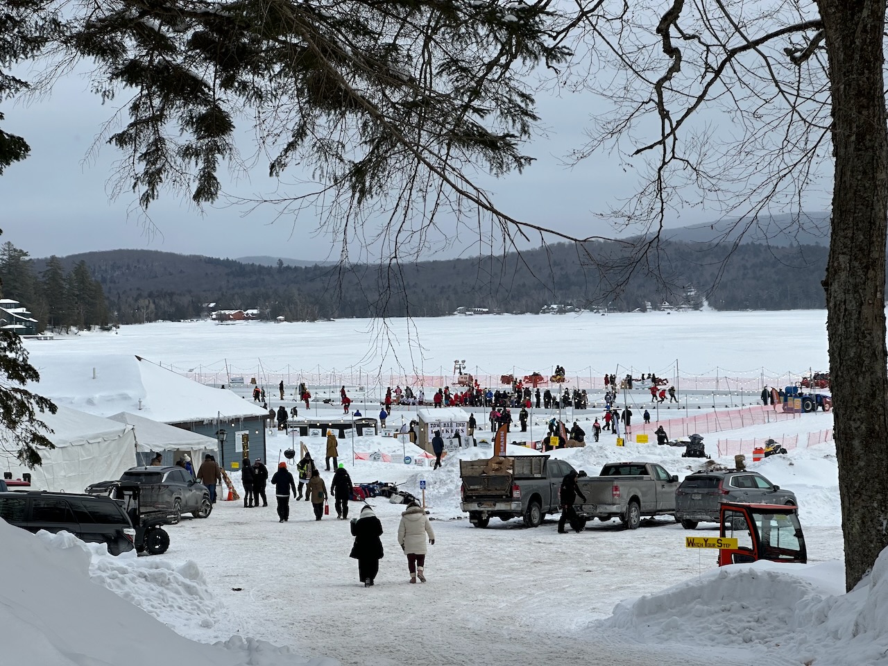 Path leading down toward hockey tournament on ice. Tents, people, and rinks are visible. 