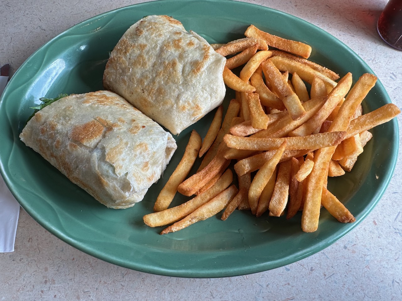 Wrap sandwich and fries on plate. 