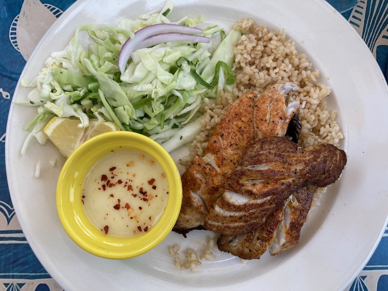 Grilled fish, rice, and salad on white plate. 