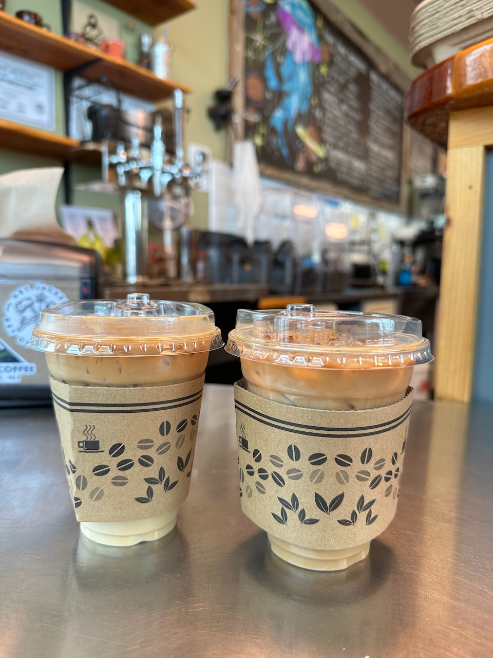 Two iced coffees on counter in coffee shop. 