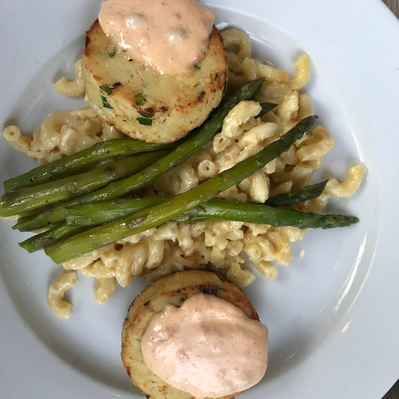 Crab cakes, asparagus, and macaroni salad on plate.