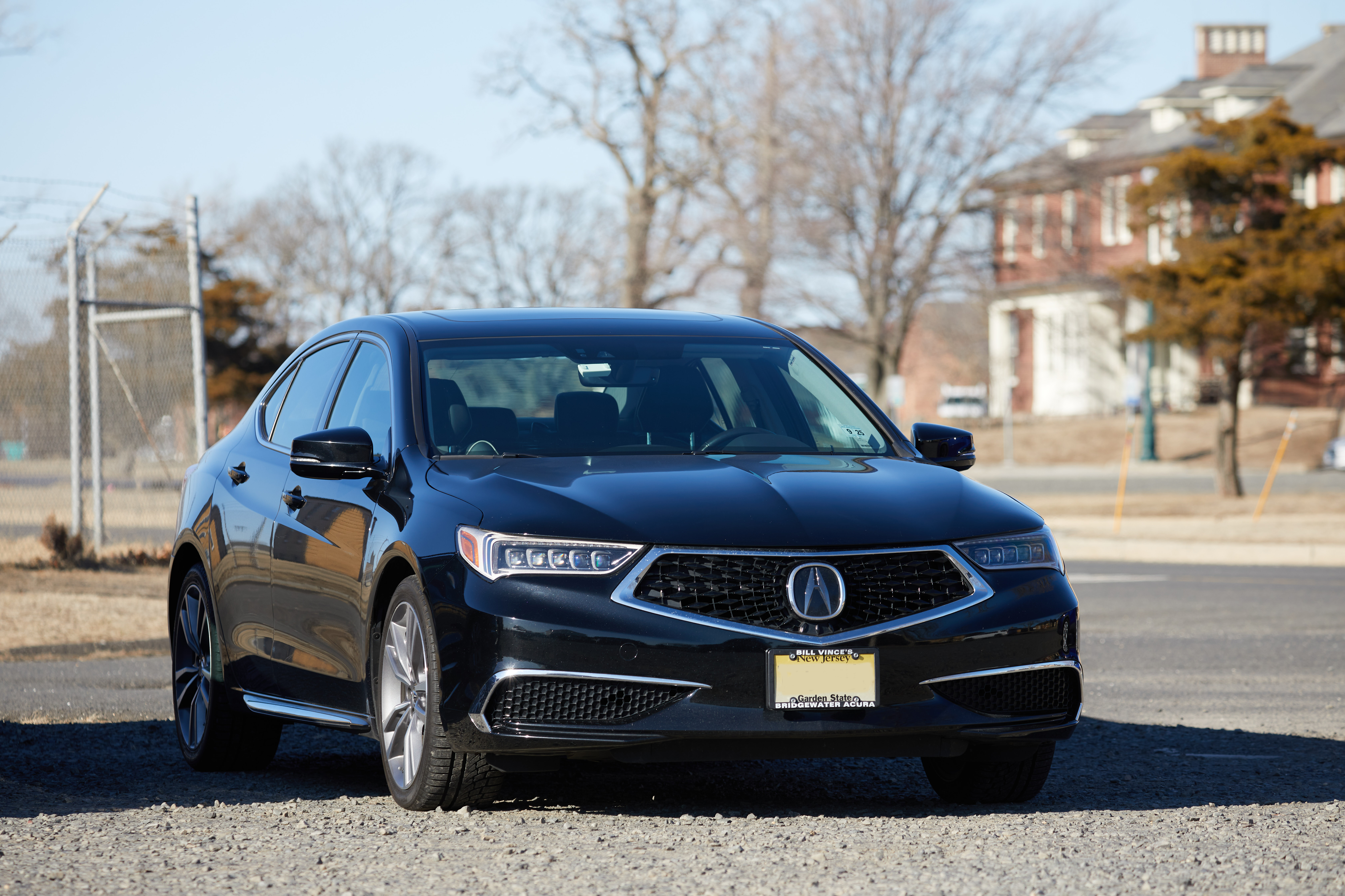 2020 Acura TLX parked on gravel lot. Brick buildings are in the background. 