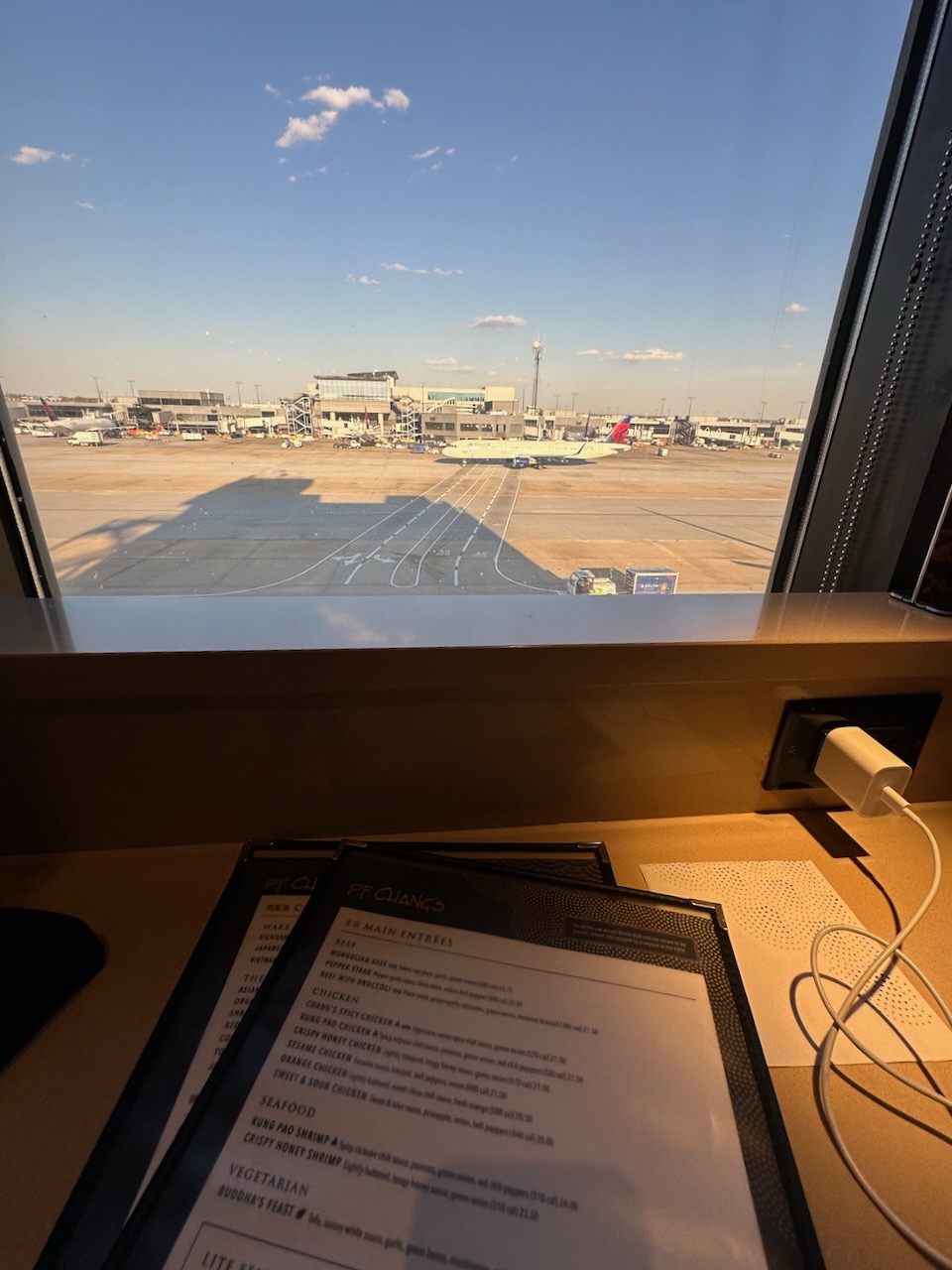 Menu on counter in front of window, with view through window of Atlanta Airport. 