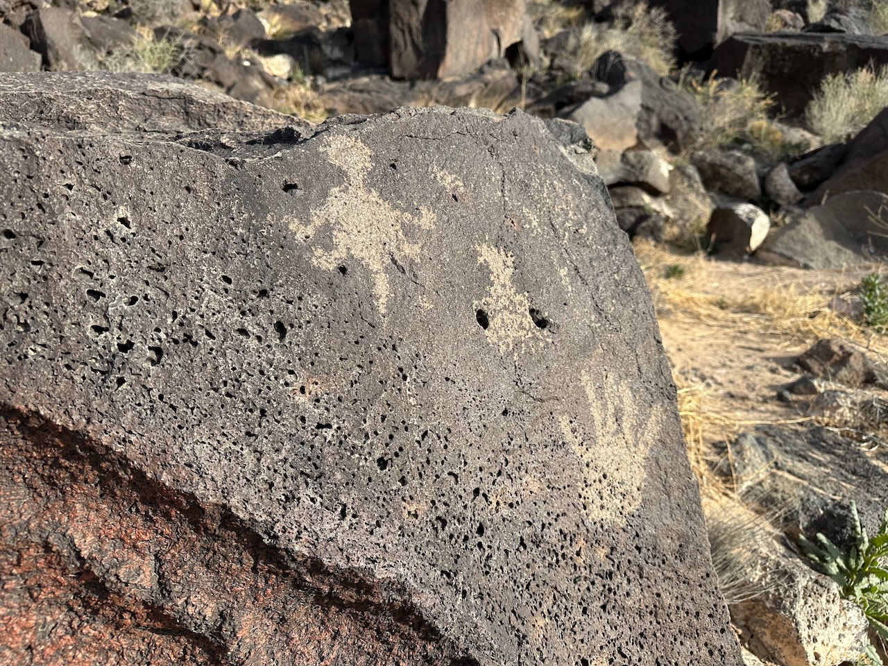 Petroglyphs of a hand and a lizard on a rock. 