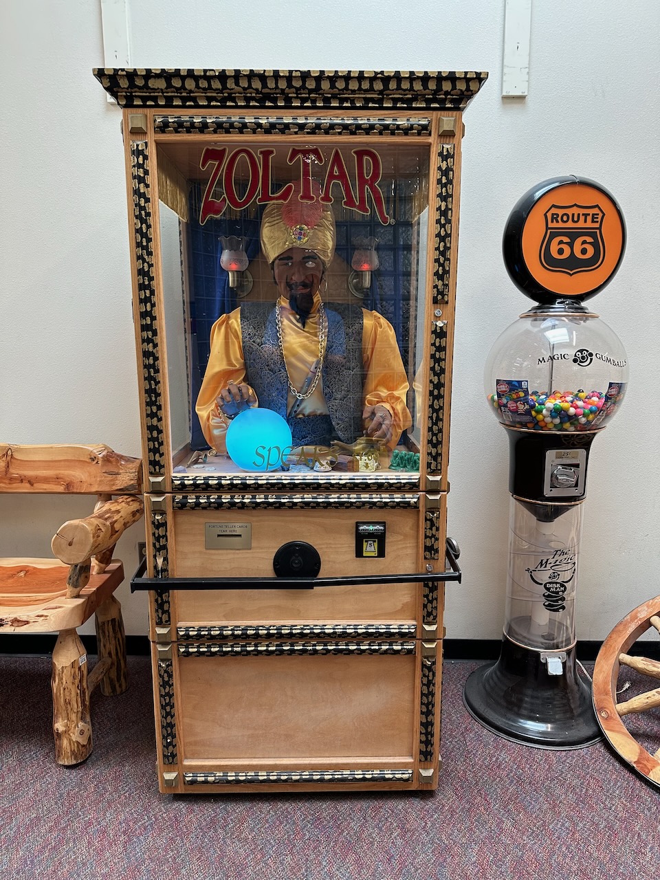 Zoltar fortune telling machine against white wall, with bubble gum machine beside it. 