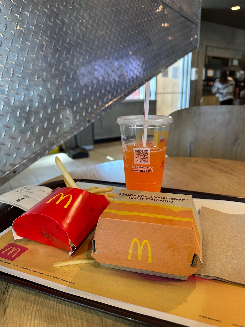 Tray with quarter pounder with cheese, fries, and a soda on table in UFO-shaped McDonalds.