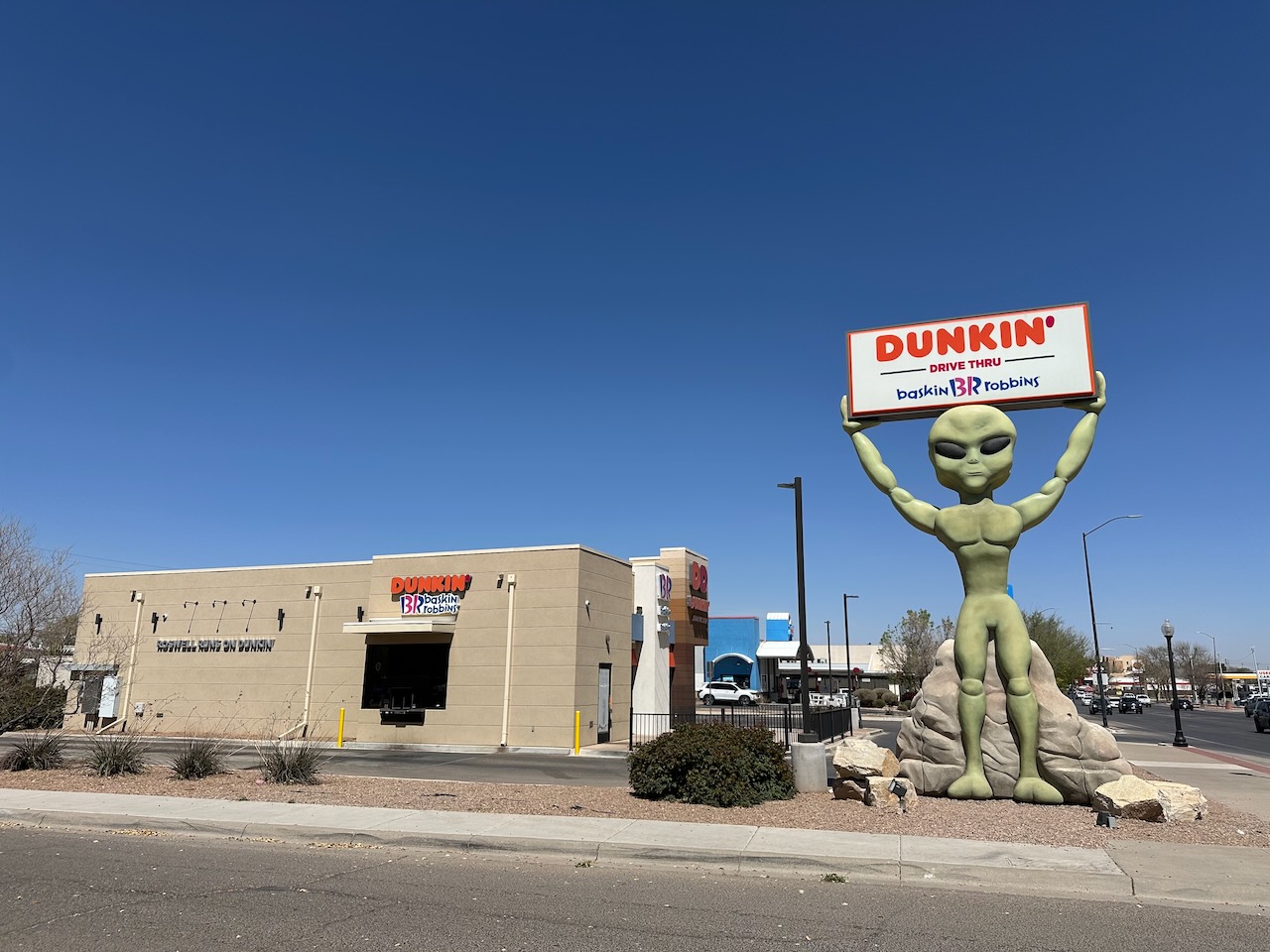 Dunkin Donuts franchise with alien statue holding Dunkin sign. 