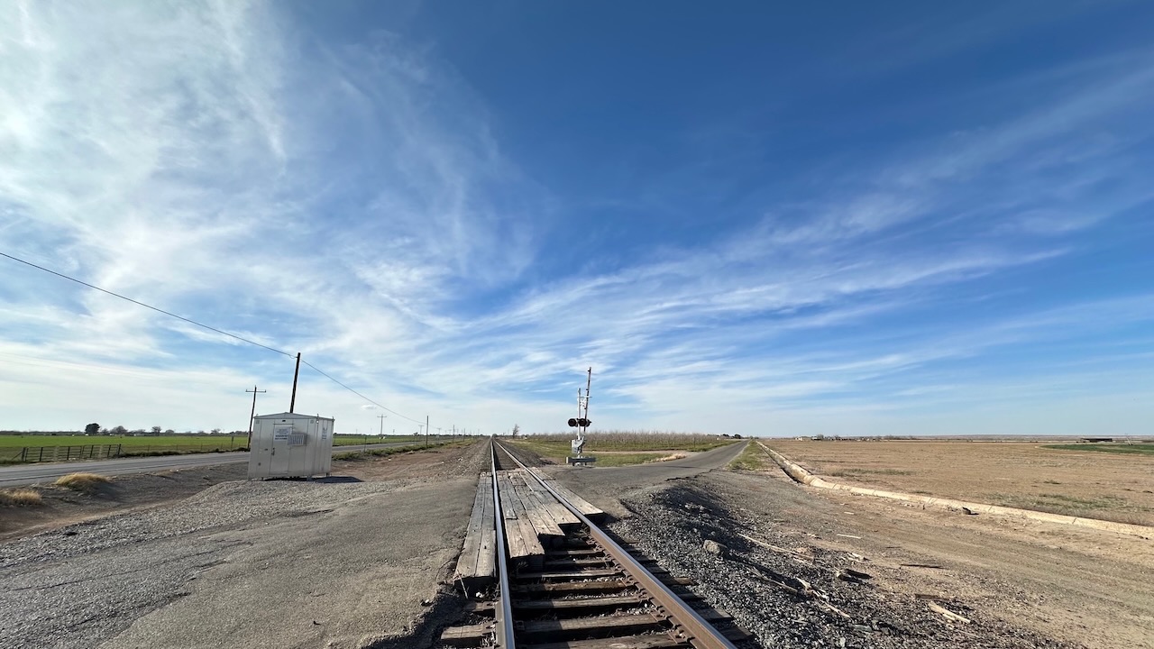 Panorama of train tracks and surrounding farm land. 