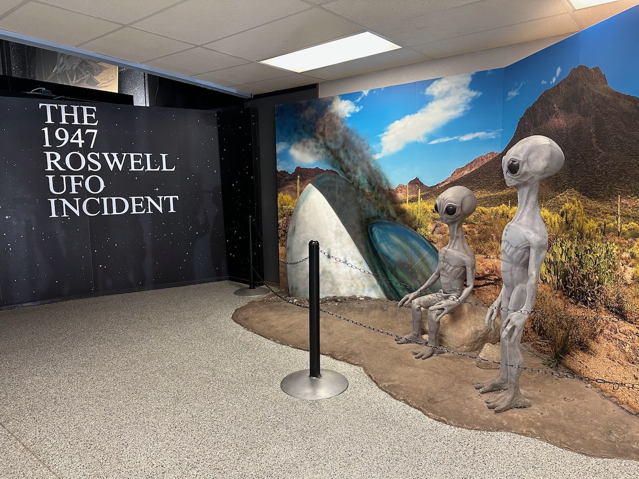 Entrance hall to museum with sign that says THE 1947 ROSWELL UFO INCIDENT and has a diorama with two alien statues. 
