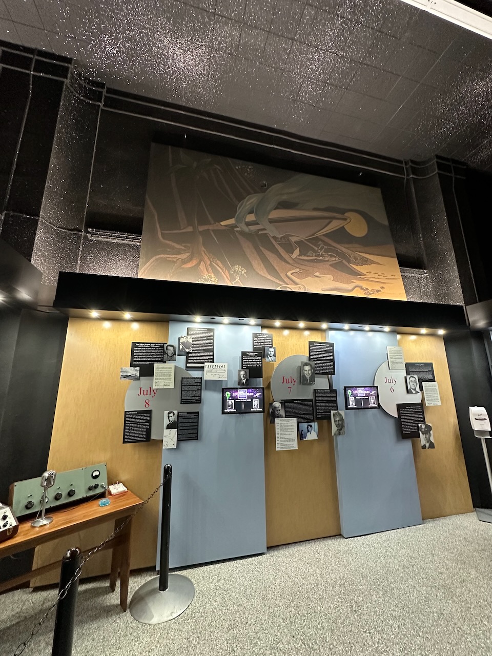 Display of information about UFO crash, with large mural of UFO high atop wall.