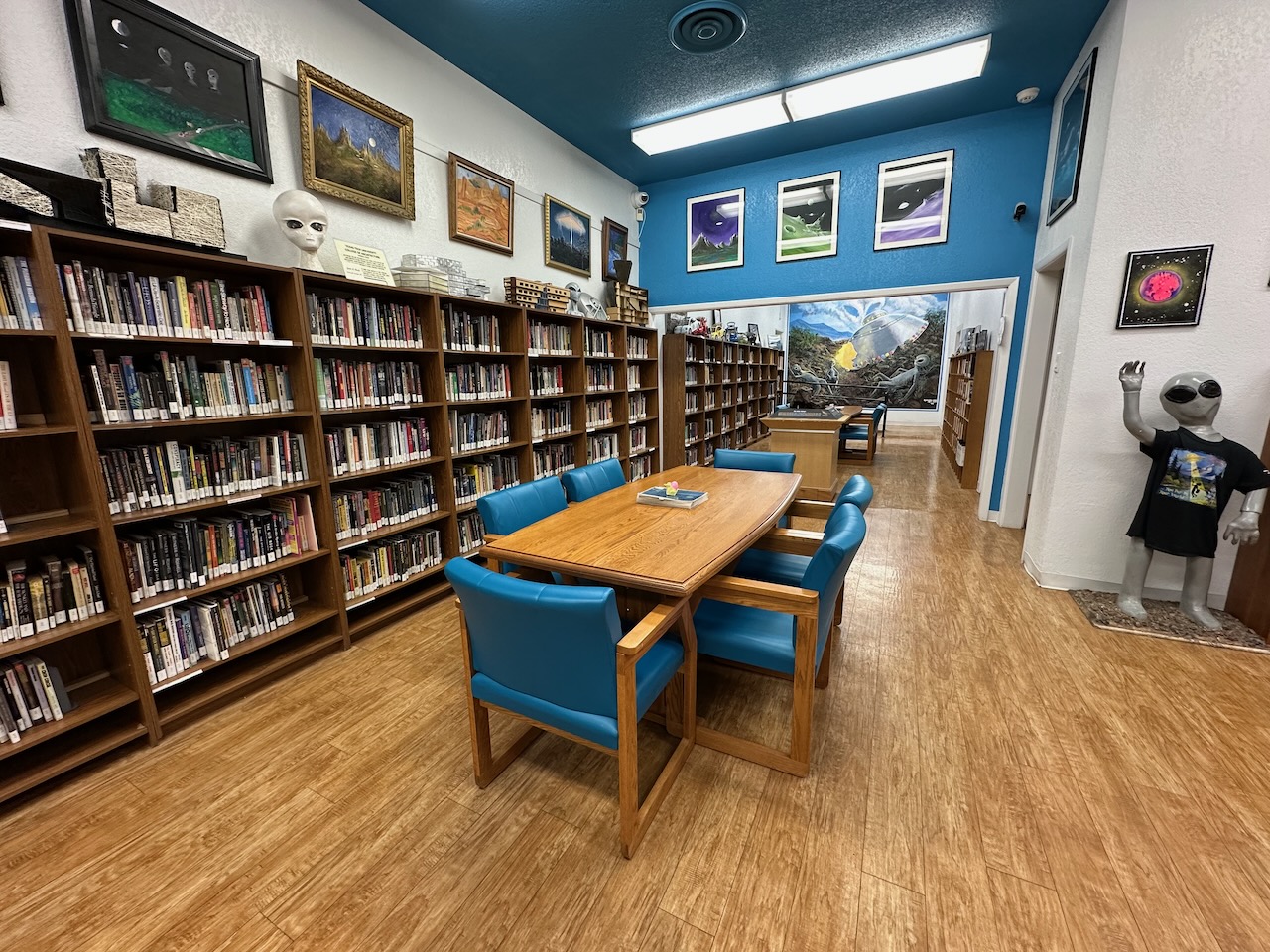 Library of UFO Museum with wooden table and chairs in center of room. Bookcases line the walls.