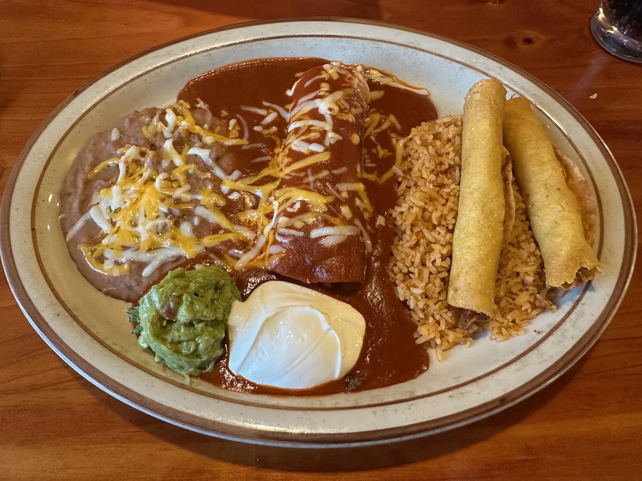 Enchiladas and flats on plate, with sides of rice and beans. 