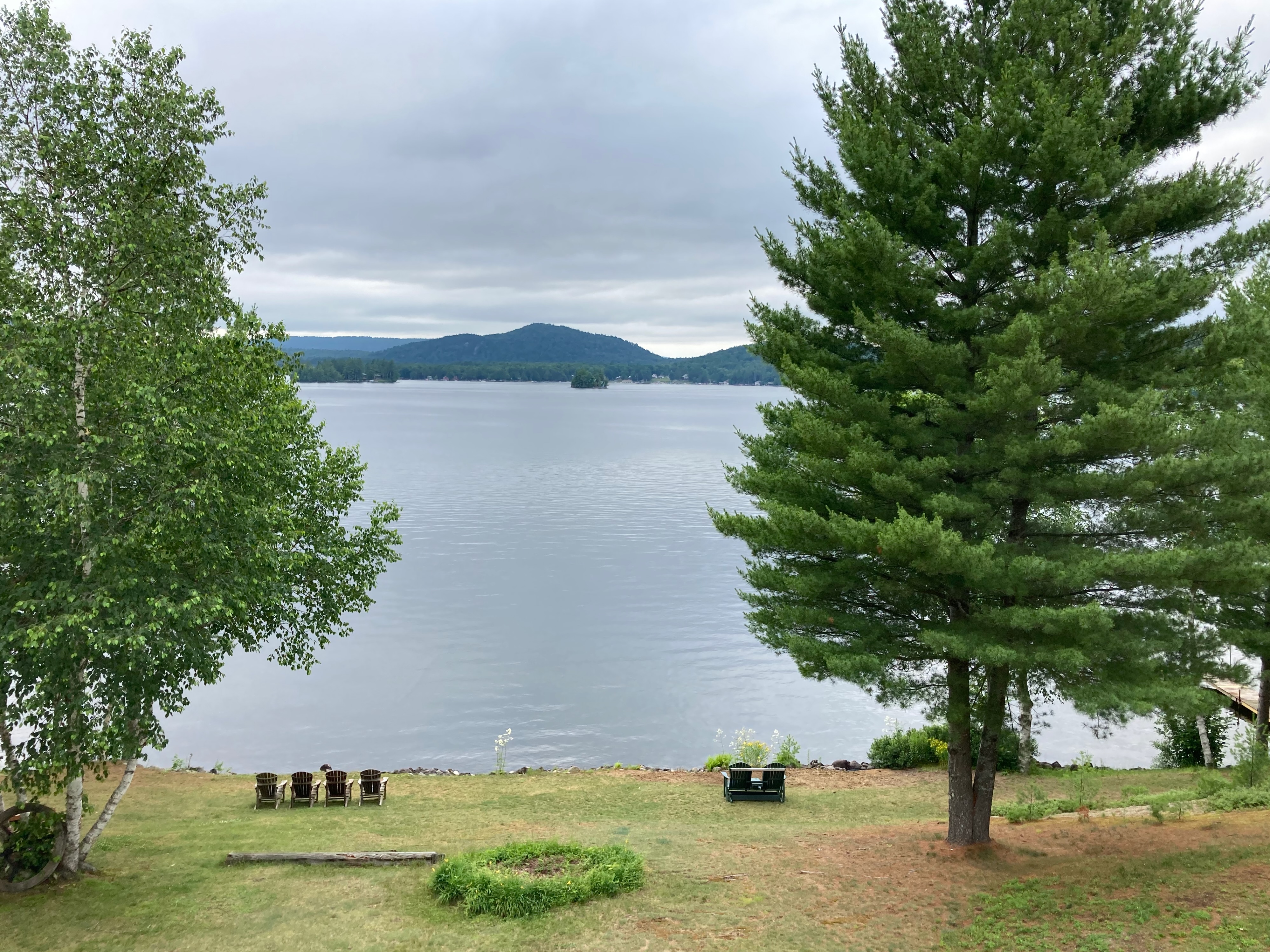 View of Fourth Lake, with trees and lawn in foreground. 