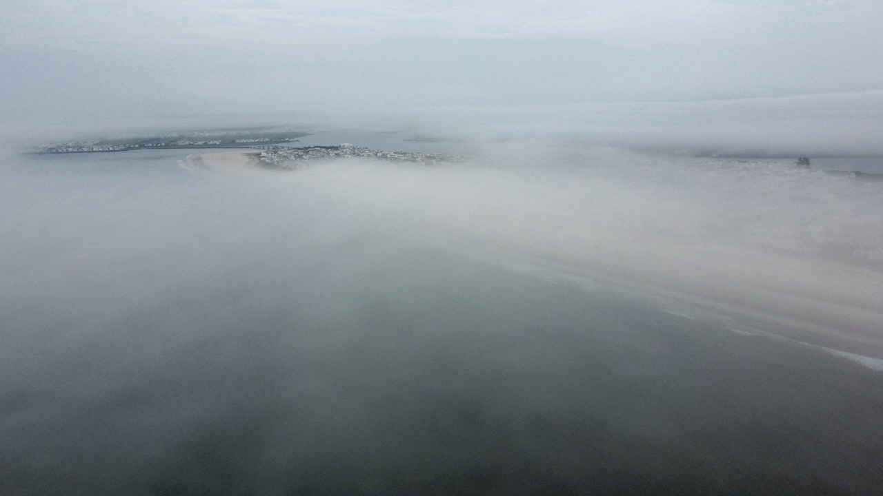 Fog-covered beach and town taken from drone. 