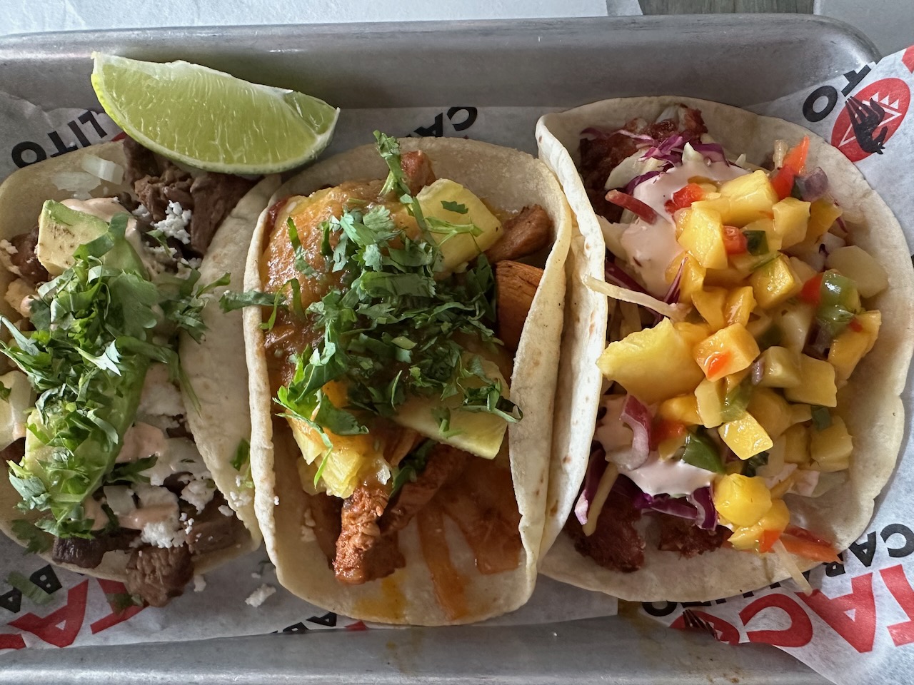 Three tacos with soft shell tortillas on plate. 