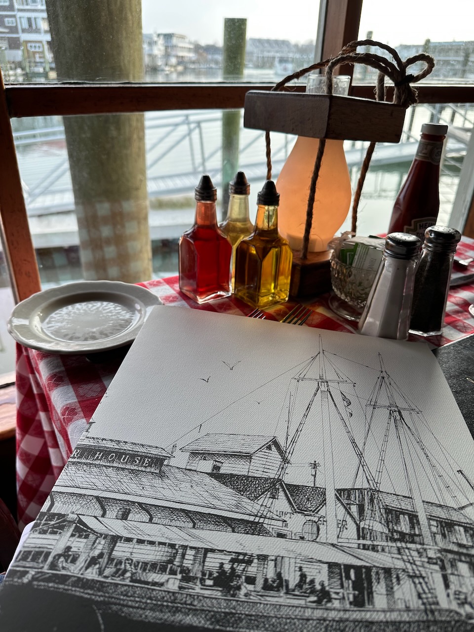 Menu on table, with view of harbor behind it. 