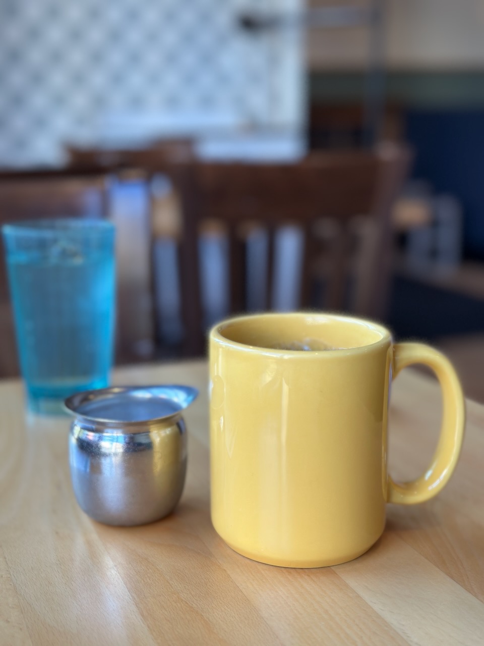 Coffee cup and creamer on table. 