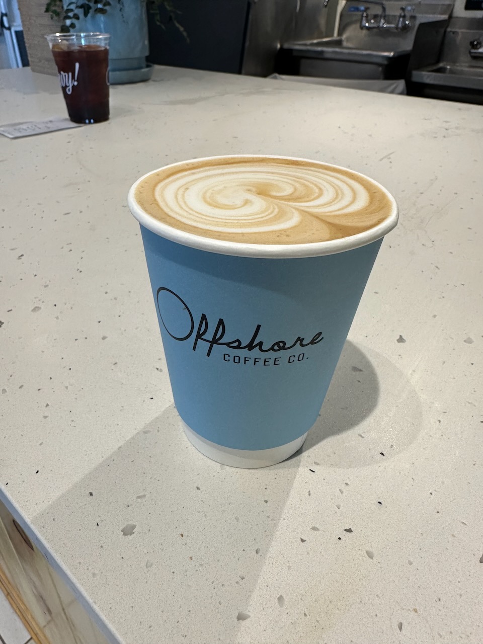 Latte in blue cup that says OFFSHORE COFFEE CO