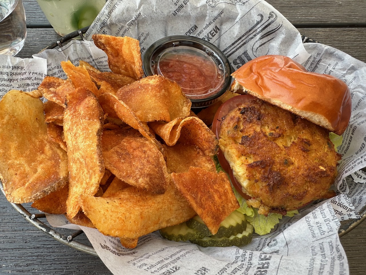 Crabcake sandwich with homemade potato chips in basket.