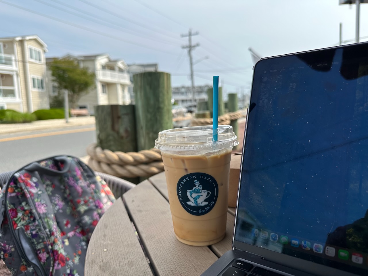 Iced latte on patio table next to MacBook Pro. 