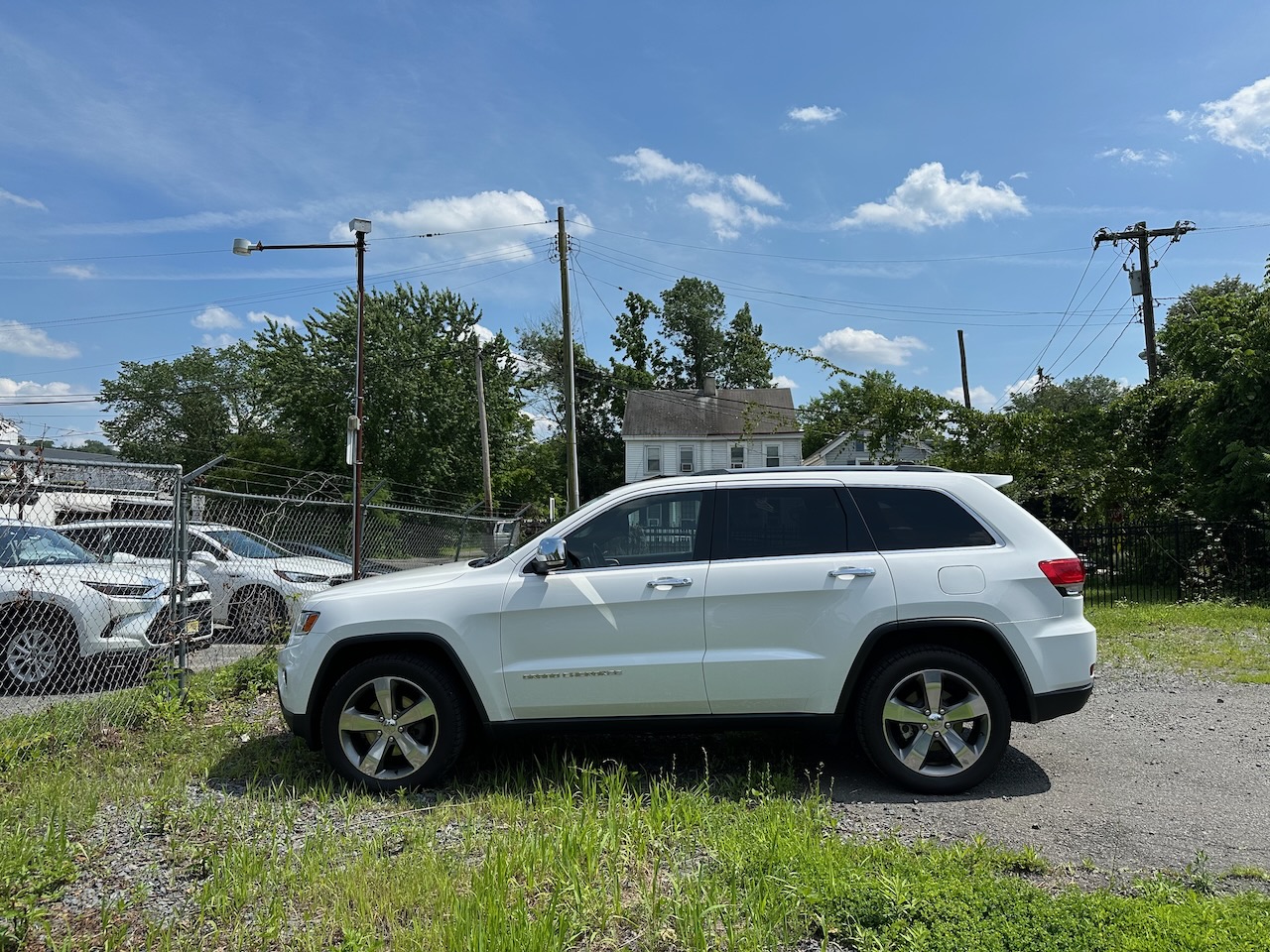 2014 Jeep Grand Cherokee parked in gravel and dirt parking lot. 