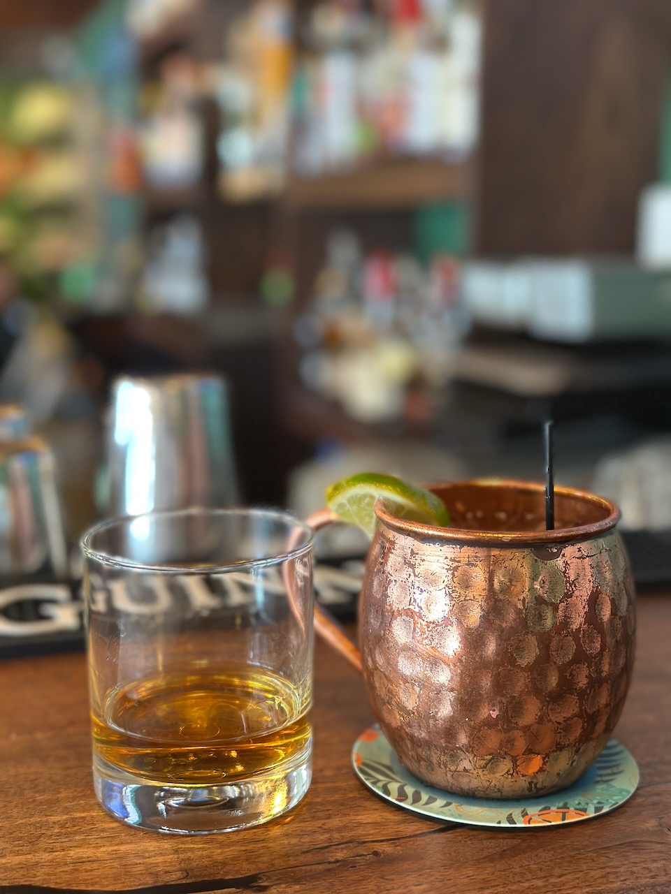 A glass of whiskey and a mule glass on table. 