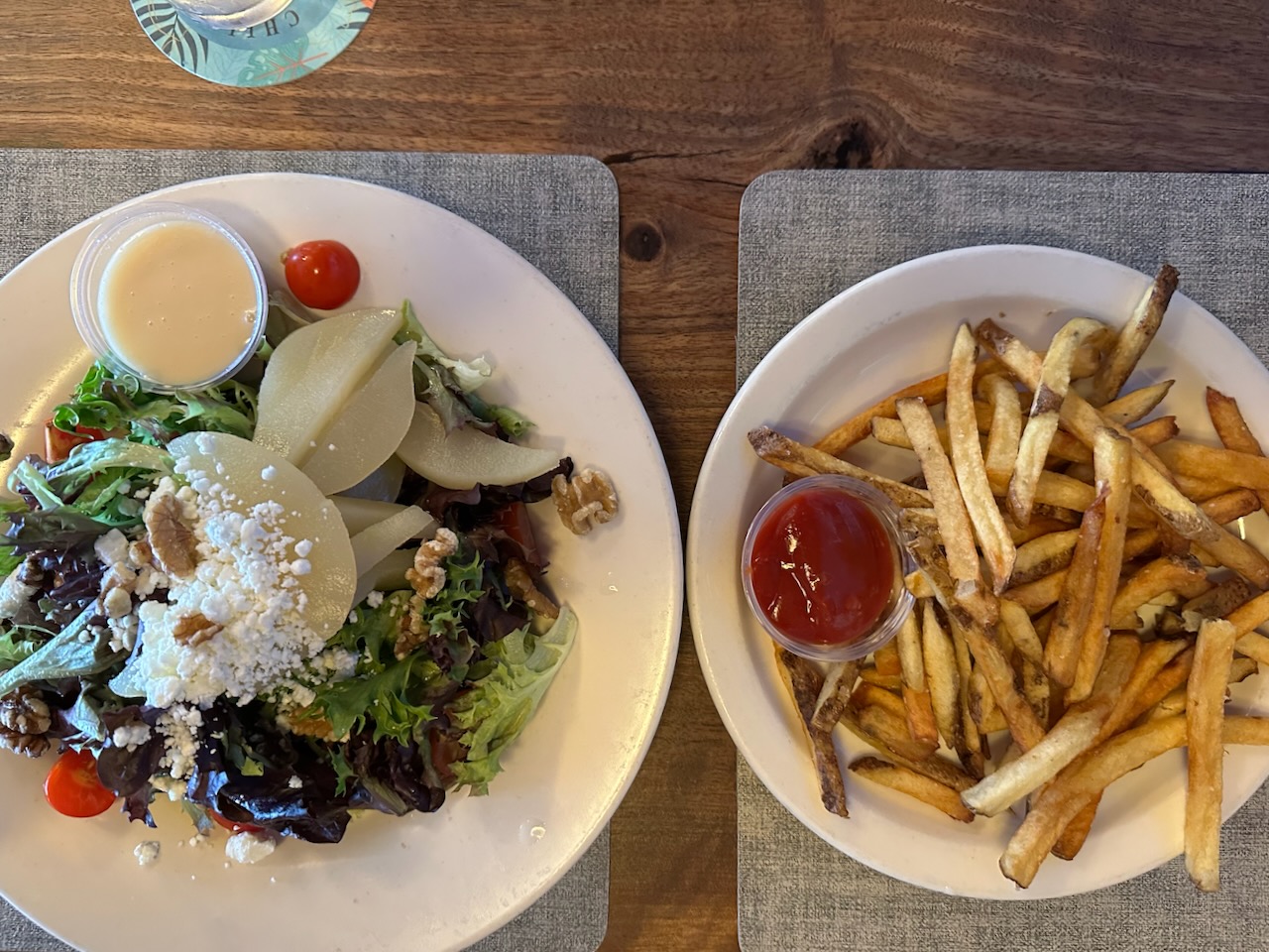 Pear salad on white plate beside french fries on white plate. 