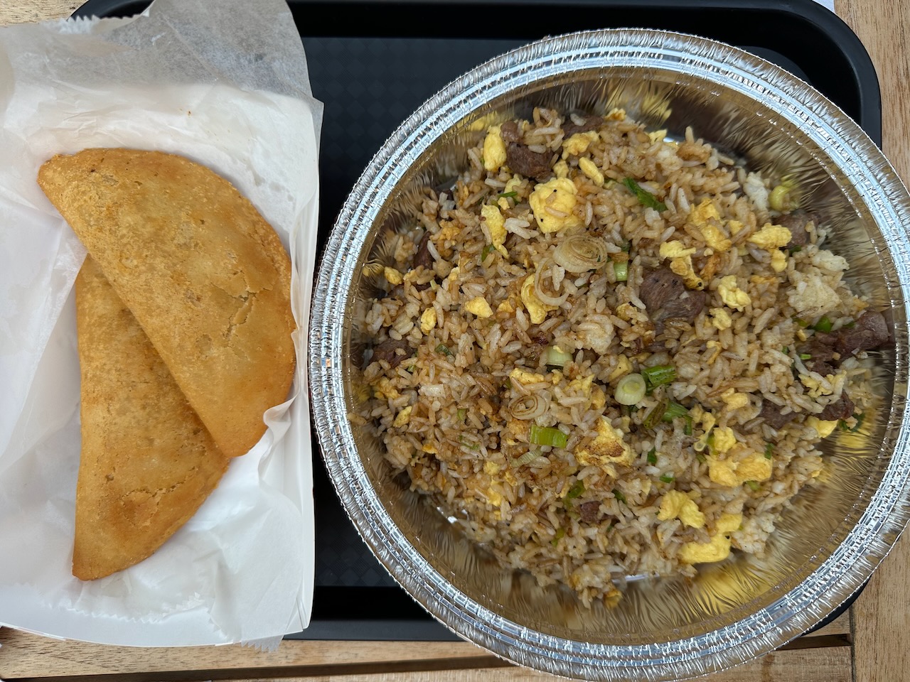 Basket with two empanadas and silver tin with chaufa.