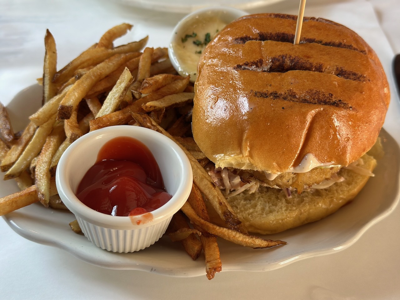 Crabcake sandwich and fries on plate. 
