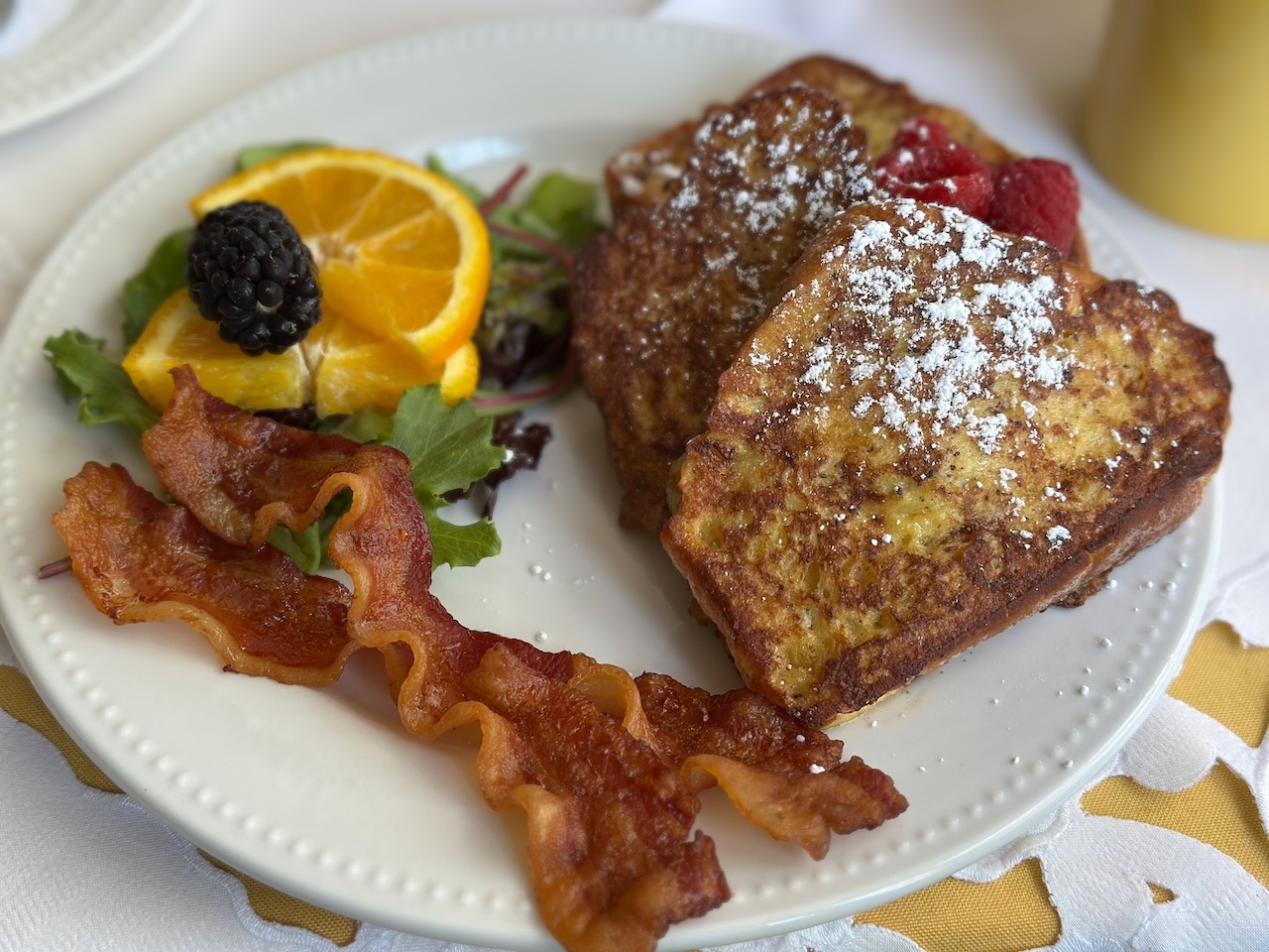 French toast, bacon, and oranges on plate. 