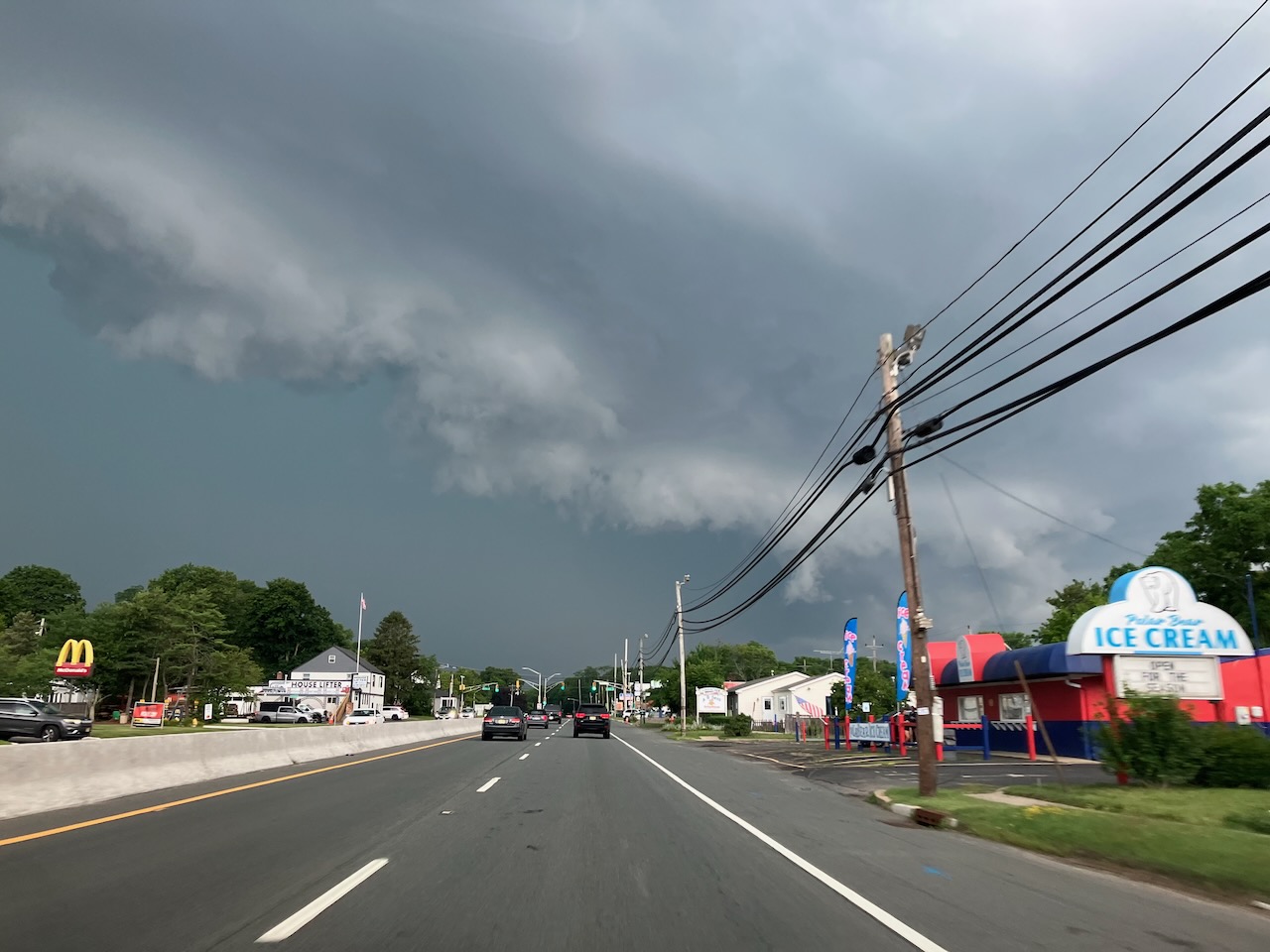 Dark gray and green clouds on horizon in distance above roadway. 