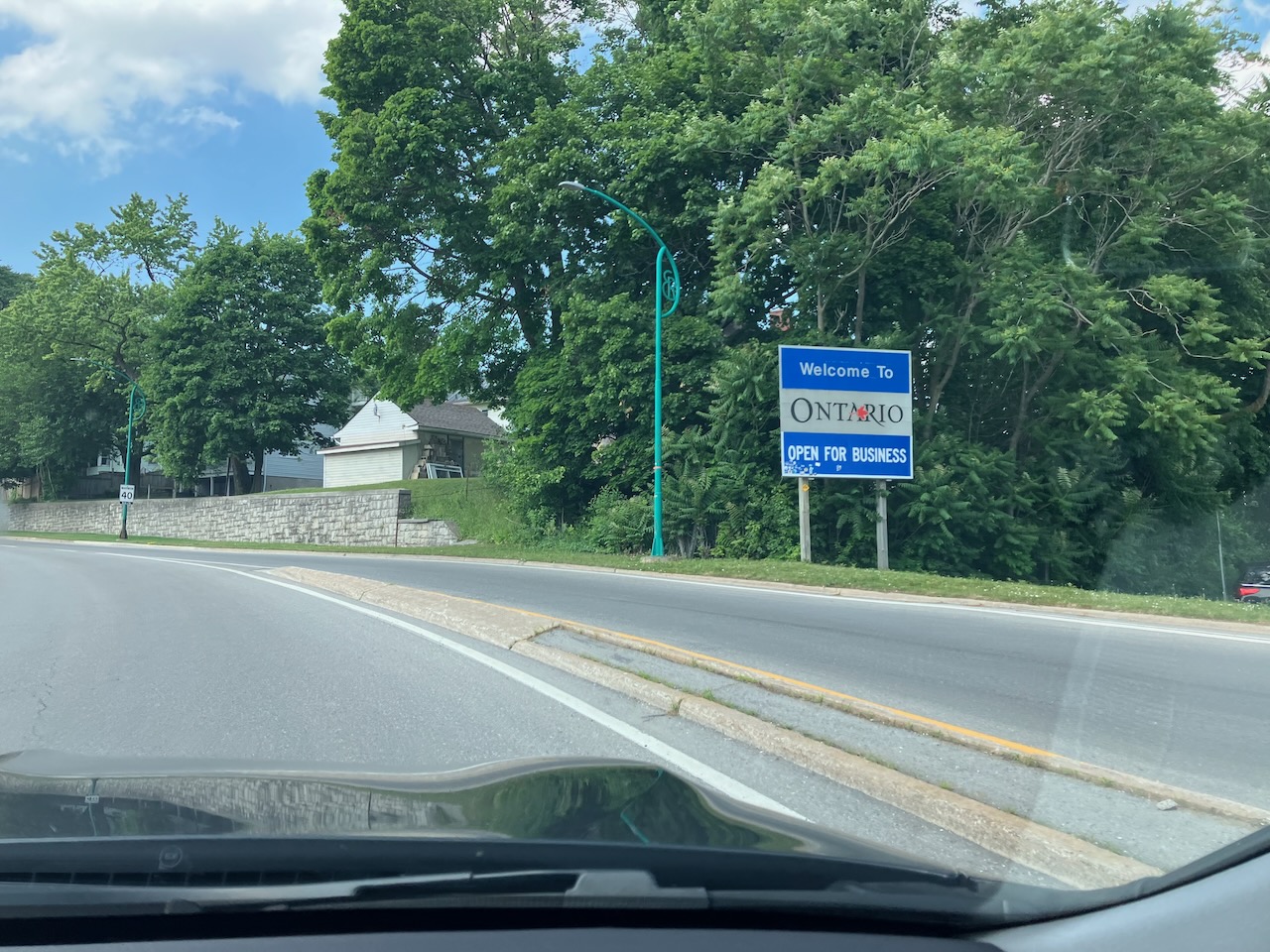 Sign beside road that welcomes visitors to Ontario. 