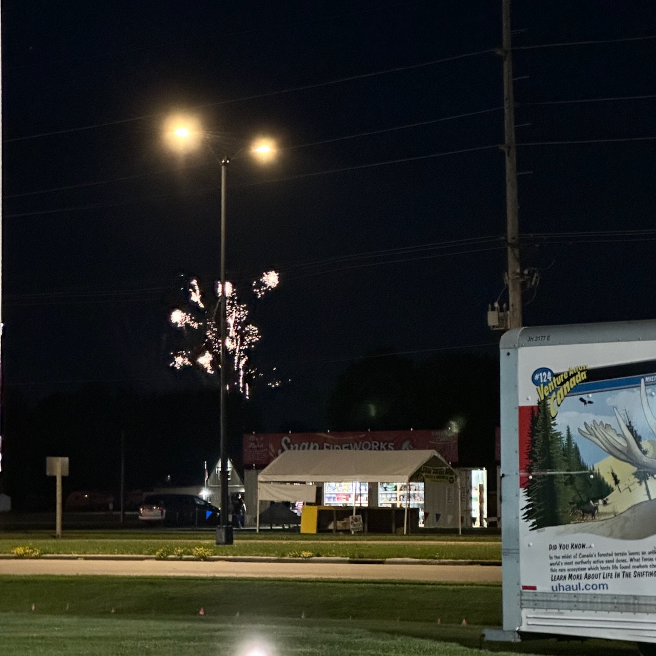 Fireworks over building in distance at night.