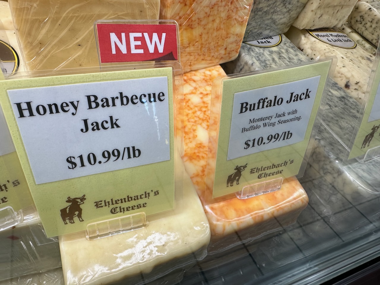 Cheeses in refrigerated display case.