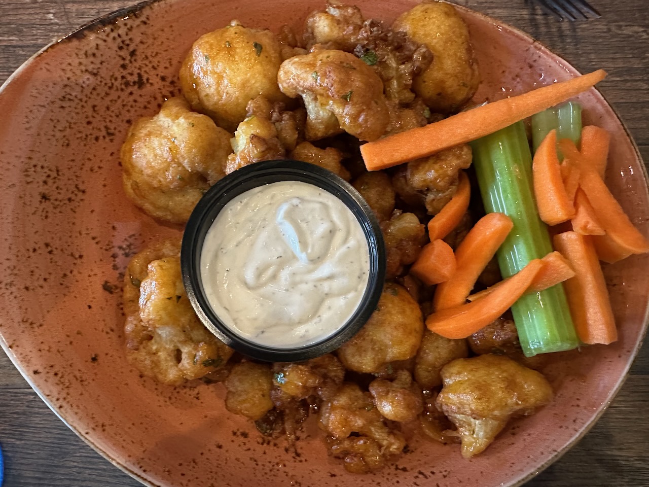 Plate of cauliflower bites with dish or ranch dressing in middle.