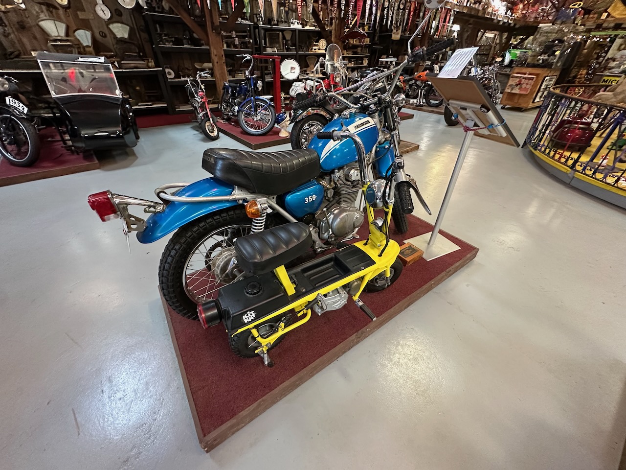 Honda CB350 in blue on display stand in middle of floor.