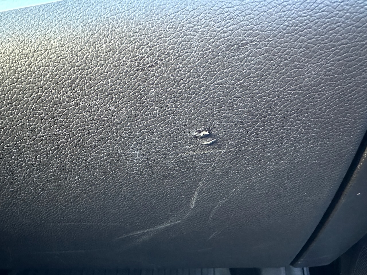 Tear in soft-touch covering of glove compartment.