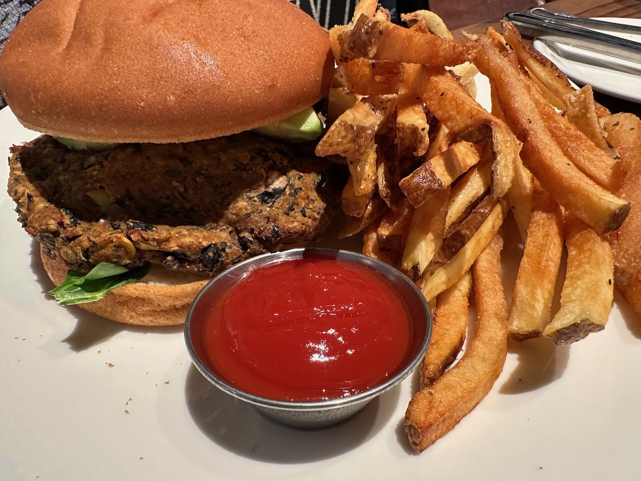Crab cake sandwich with fries on white plate.