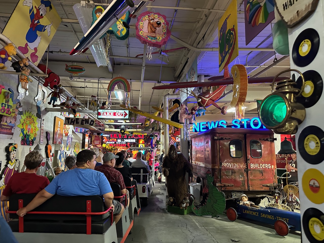 Tram cars lined up to tour through museum, with people seated in tram.