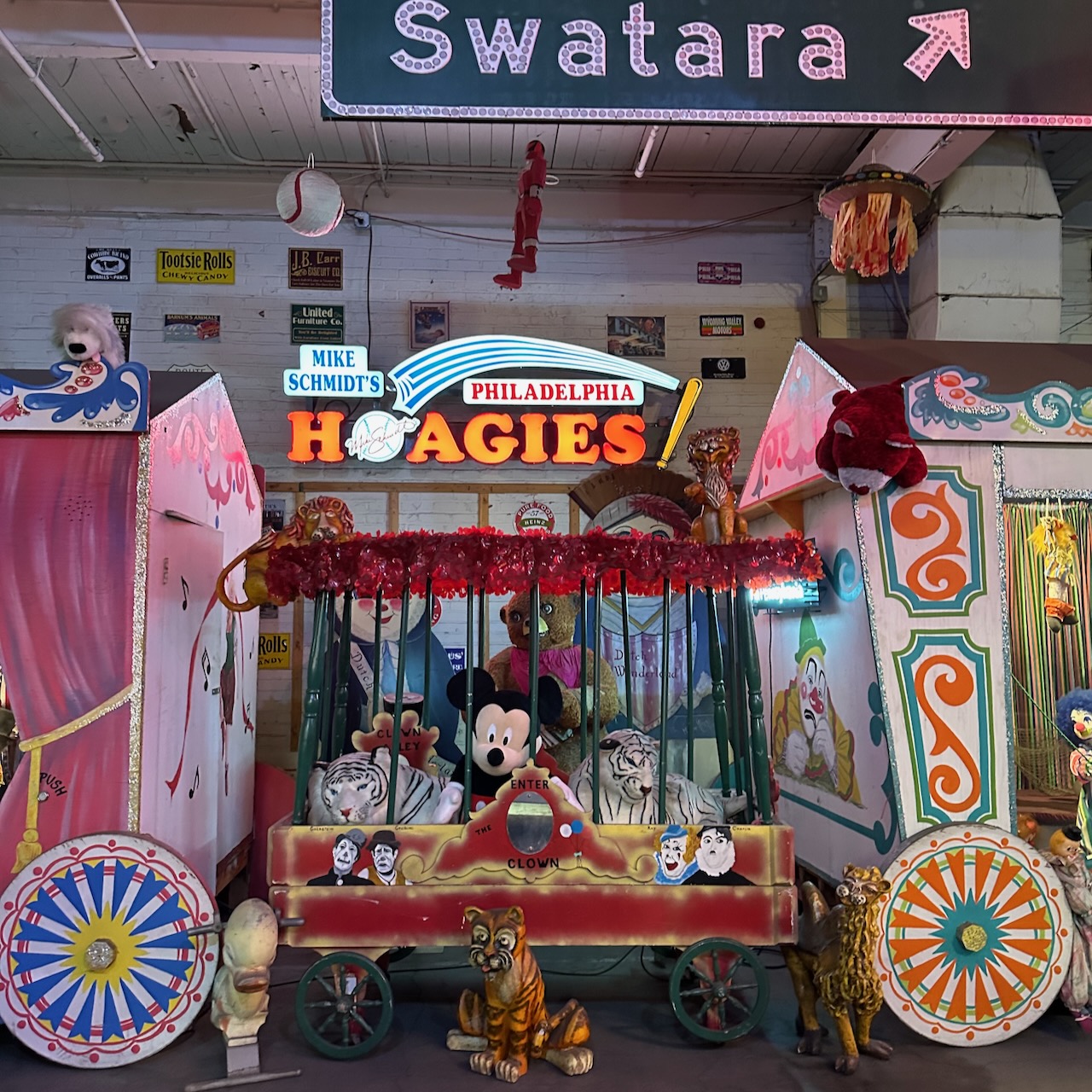 Circus wagons in foreground, with neon sign in background for Mike Schmidt's Hoagies.