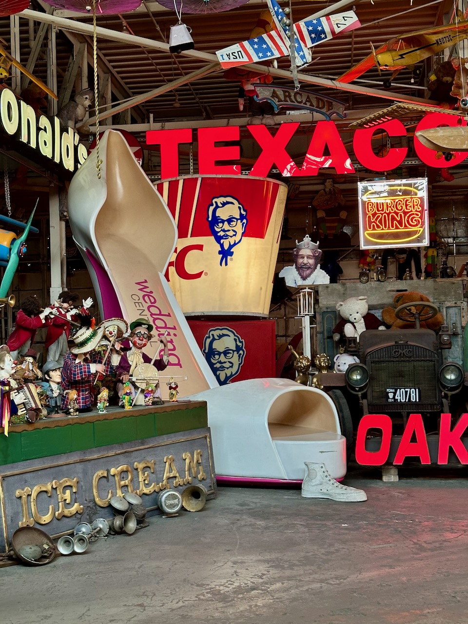 Various items including ten-foot tall high heeled shoe, Texaco neon sign, and giant Kentucky Friend Chicken bucket.