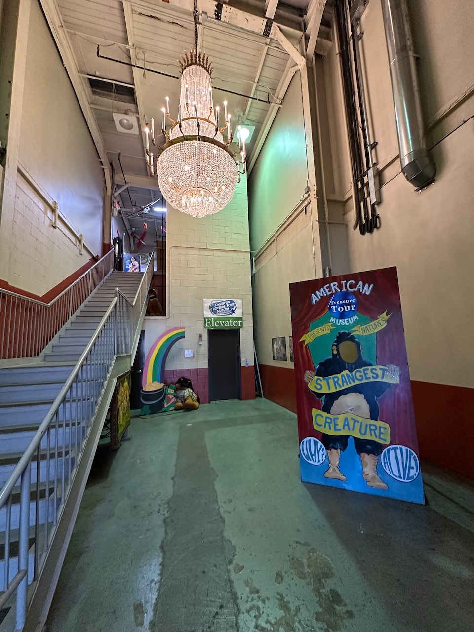 Entrance and staircase up to museum, with large chandelier hanging from ceiling.