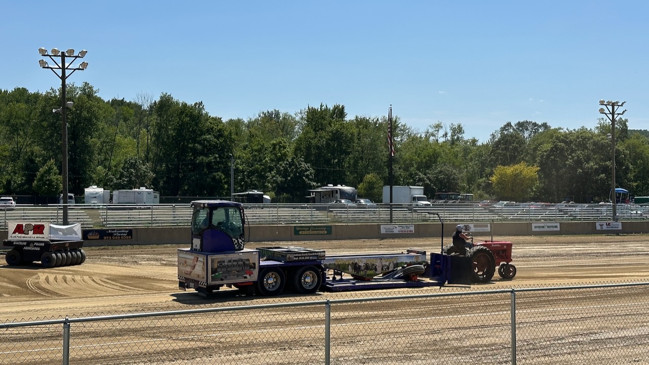 Tractor pulling a sled down a dirt track.