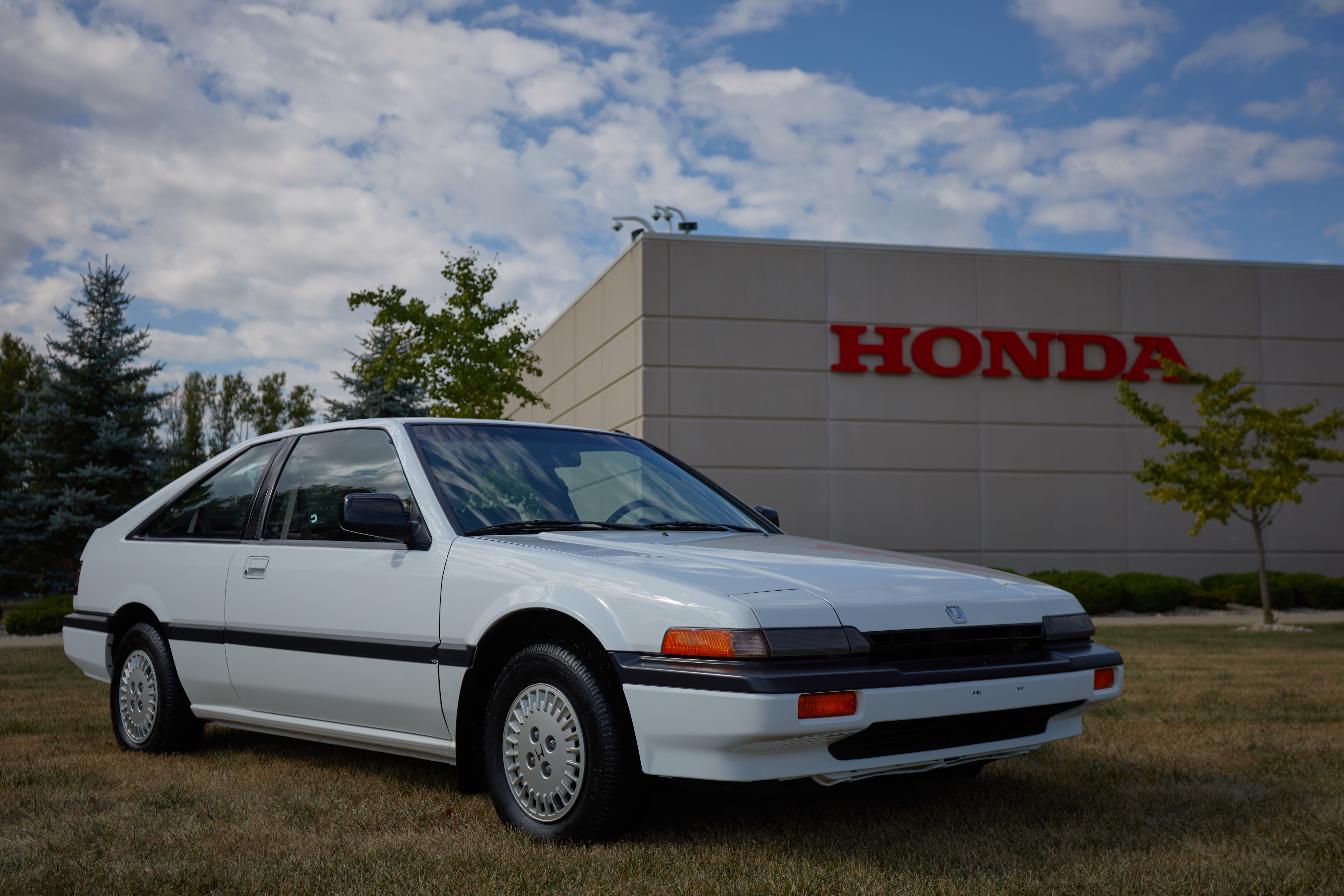3rd generation Honda Accord hatchback parked on lawn in front of Honda Heritage Center.