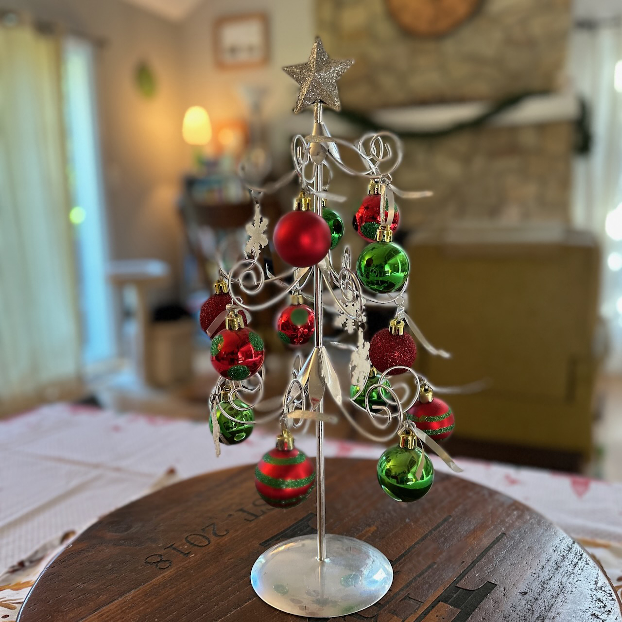 Metal christmas tree with christmas balls on table.