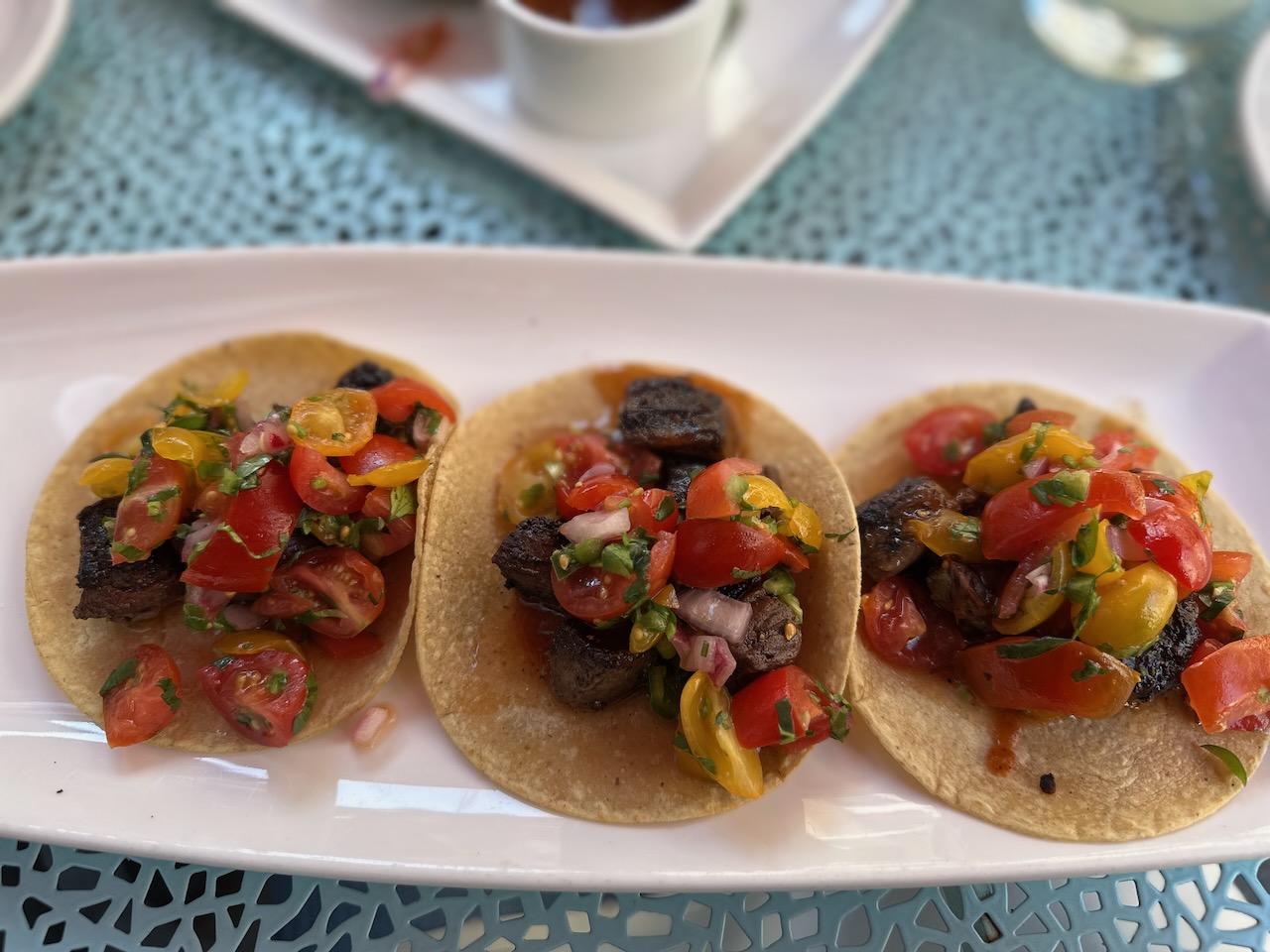 Three steak tacos on white plate. 