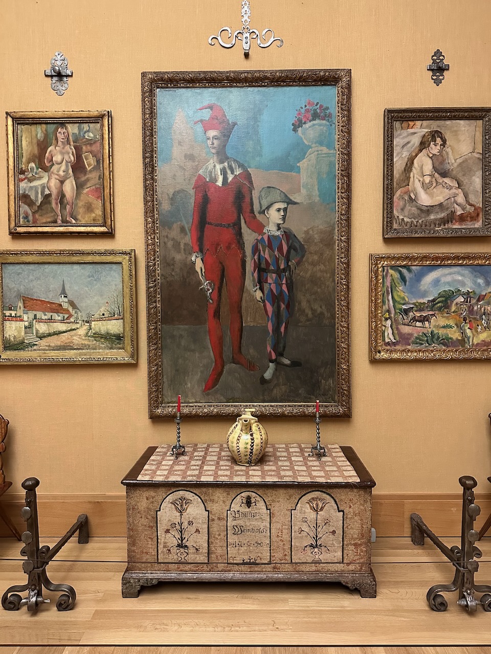 Large painting of man and child over chester, with paintings on either side of work. 